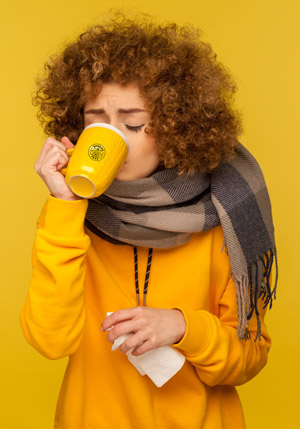 Woman drinking tea from yellow branded buddha teas mug.